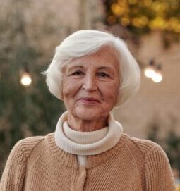 Cheerful senior woman in a cozy cardigan enjoying an outdoor gathering in the garden.